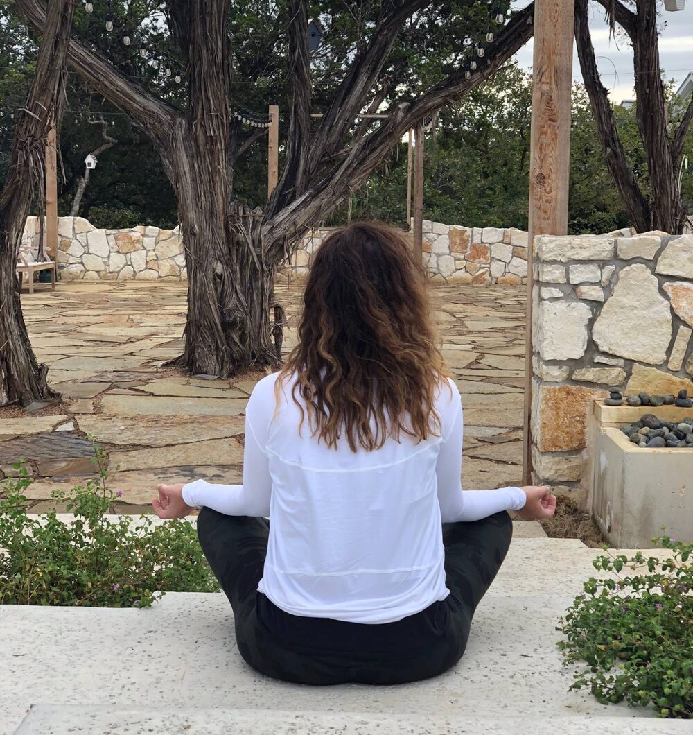 Dana Katz meditating in a quiet stone courtyard