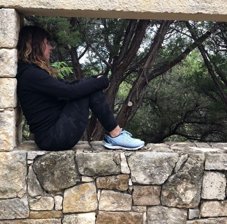 Dana Katz sitting in a stone window, looking out at the trees