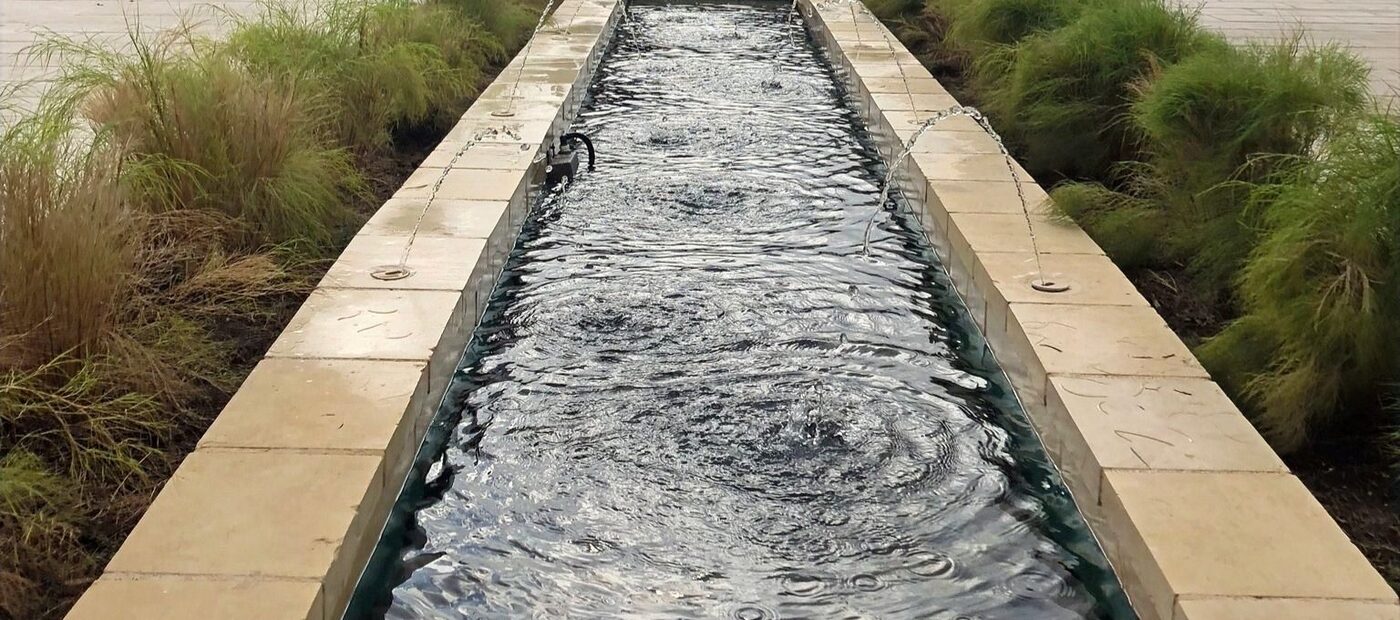 A long, calm reflecting pool lined with soft grasses